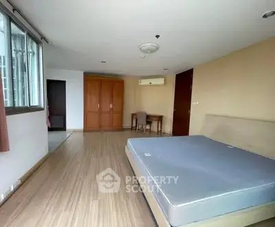 Spacious bedroom with wooden flooring and large window in modern apartment