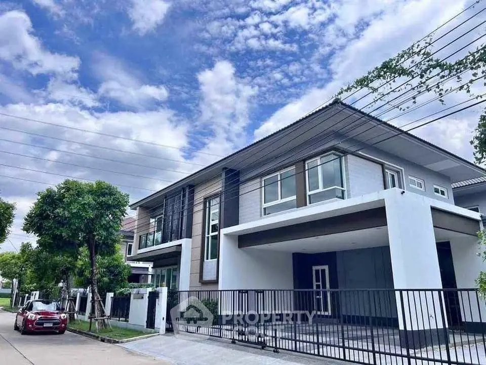 Modern two-story house with sleek design and spacious driveway under a vibrant blue sky.