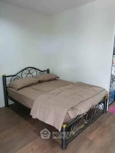 Cozy bedroom with metal bed frame and wooden flooring, perfect for restful nights.