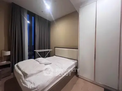 Cozy bedroom with modern furnishings and large window offering natural light.