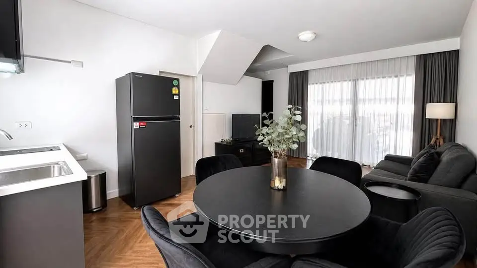 Modern living room with sleek black furniture and open kitchen layout