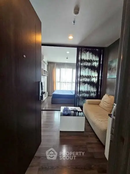 Modern apartment interior with cozy living room and bedroom view, featuring stylish decor and natural light.
