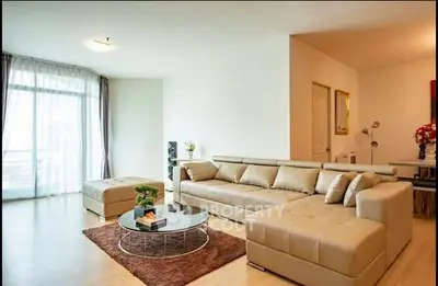 Spacious modern living room with large beige sectional sofa and natural light.