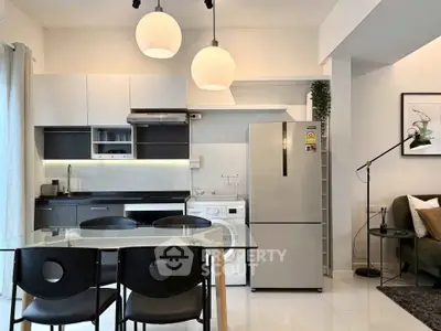 Modern kitchen with sleek appliances and dining area in open layout apartment