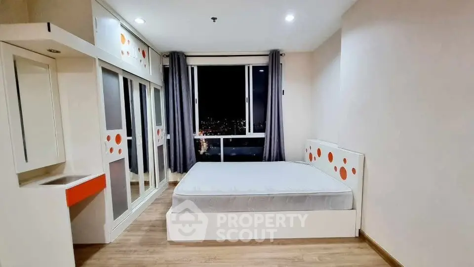 Modern bedroom with city view, featuring sleek design and ample storage space.