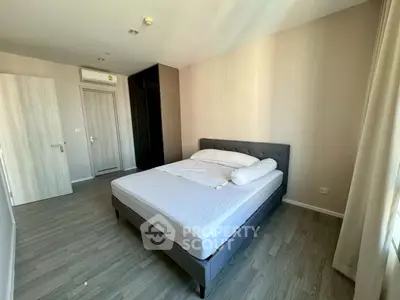 Spacious bedroom with modern decor and ample natural light, featuring a comfortable bed and sleek flooring.