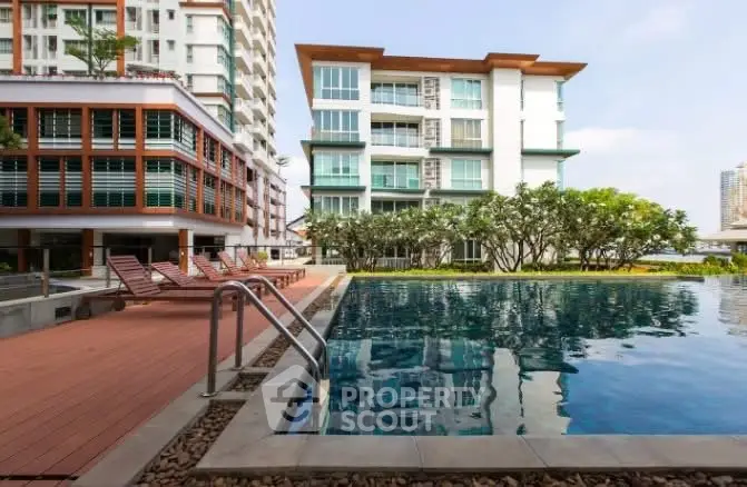 Luxurious apartment complex with modern pool and sun loungers, perfect for relaxation and leisure.