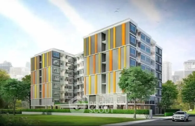 Modern apartment building with colorful facade and lush greenery in urban setting.
