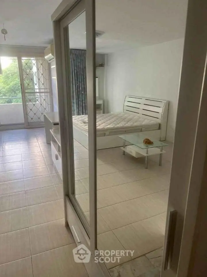Spacious bedroom with large windows and balcony access, featuring modern furniture and natural light.