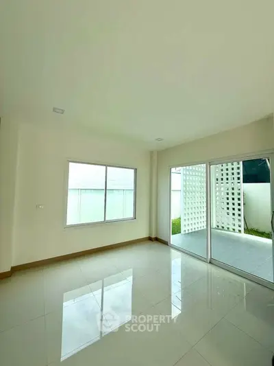Bright and spacious living room with large windows and sliding glass doors to patio.