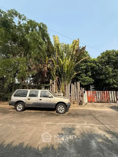 Charming rustic property with lush greenery and unique wooden fence, perfect for nature lovers.