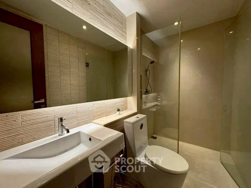 Modern bathroom with sleek design, featuring a glass shower and contemporary fixtures.