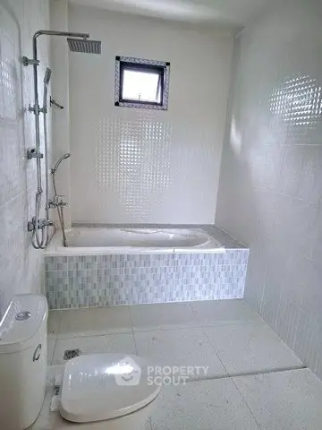 Spacious bathroom with modern bathtub and shower in a bright, tiled setting.