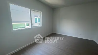Spacious empty room with large window and wooden flooring, perfect for customization.