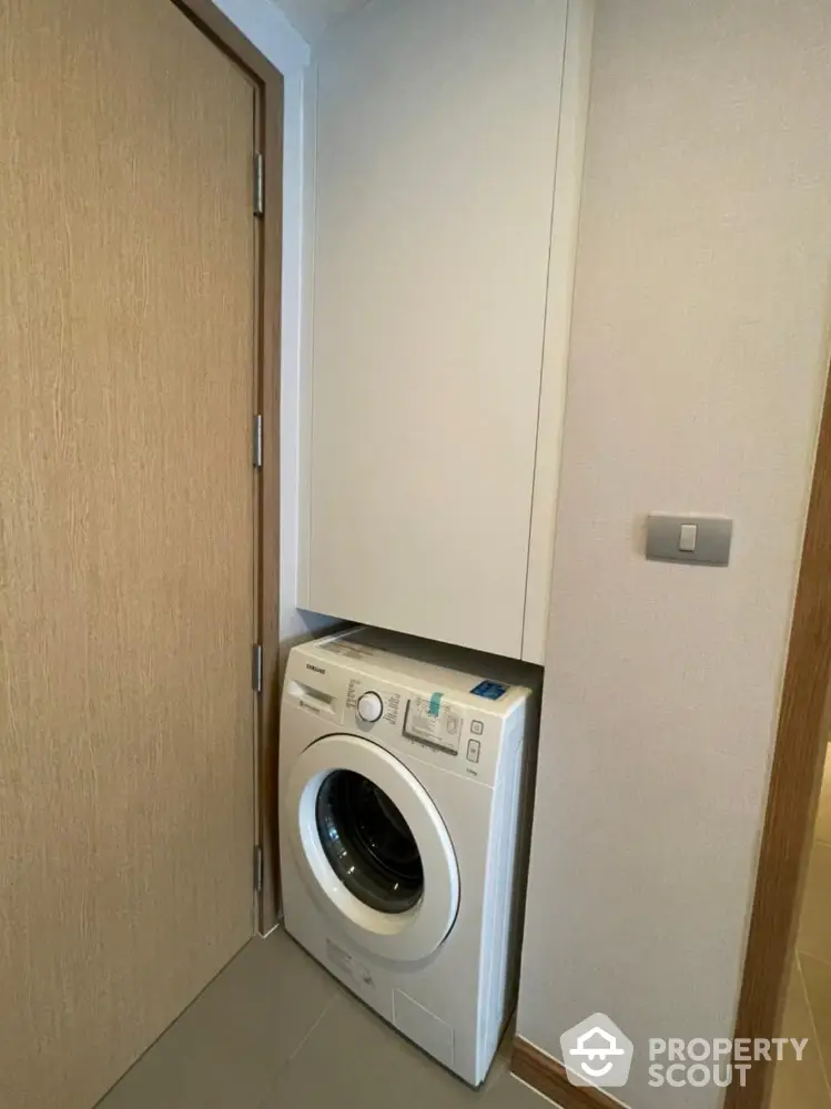 Compact laundry area with modern washing machine in a sleek apartment.