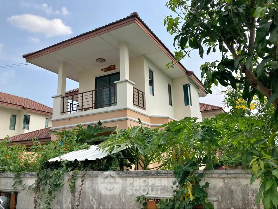 Charming two-story house with balcony and lush garden in a serene neighborhood.