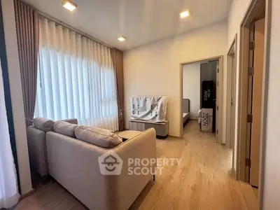 Modern living room with cozy sofa and elegant curtains, leading to a stylish bedroom.