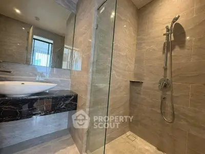 Luxurious modern bathroom with sleek marble finishes and glass shower enclosure.