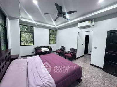 Spacious bedroom with modern ceiling fan and air conditioning, featuring elegant furniture and large windows.
