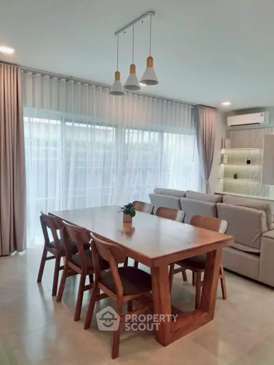 Elegant dining area with wooden table and chairs, modern lighting, and cozy ambiance.