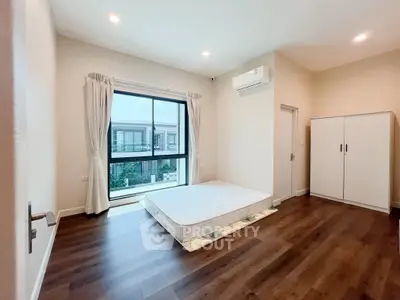 Spacious bedroom with large window and modern air conditioning unit