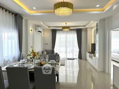 Luxurious open-plan living and dining area with elegant chandeliers and modern decor.