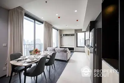 Modern open-plan living and dining area with city view, featuring elegant decor and ample natural light.