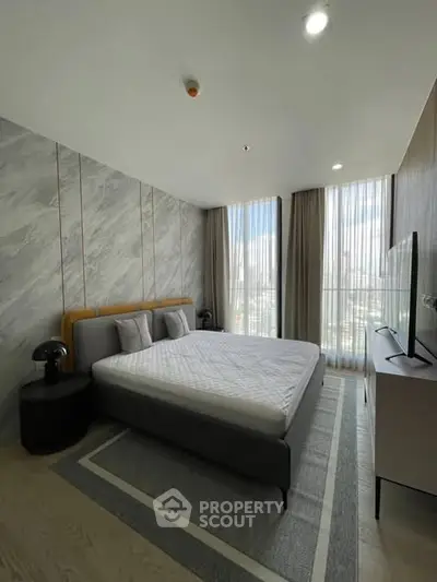 Modern bedroom with large windows and stylish decor in a high-rise apartment.