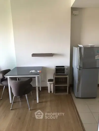 Modern kitchen with dining area featuring a sleek table, chairs, and a stainless steel fridge.