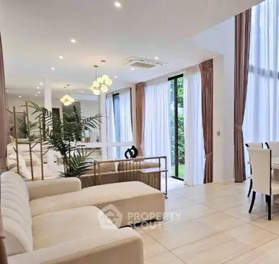 Luxurious open-plan living room with elegant decor and large windows offering garden views.