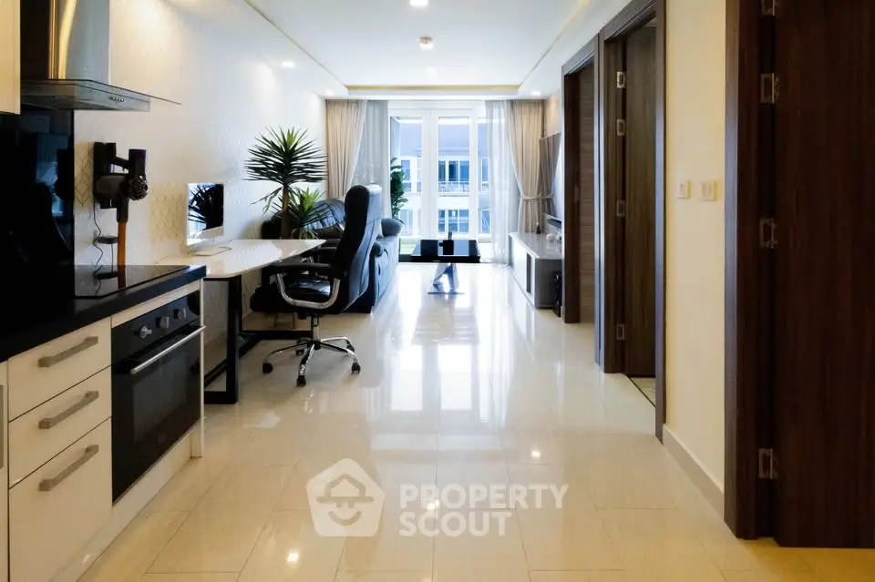 Modern open-layout living room with sleek kitchen and large windows.