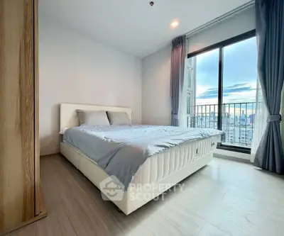 Spacious bedroom with large window offering stunning city views and modern furnishings.