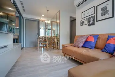 Modern living room with stylish decor and dining area, featuring leather sofa and elegant lighting.
