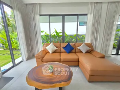 Spacious living room with modern leather sofa and garden view, perfect for relaxation and entertaining.