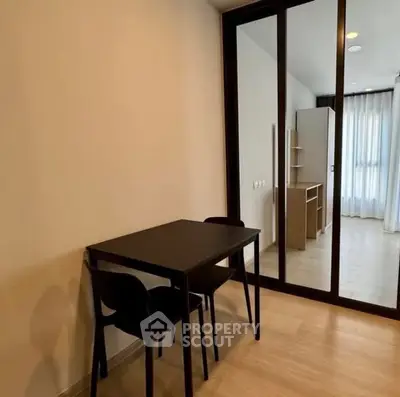 Modern minimalist study area with sleek black furniture and mirrored closet doors.