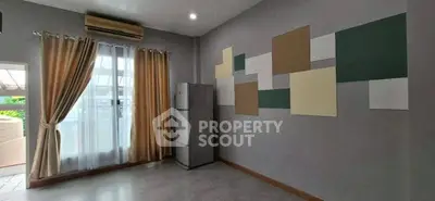 Spacious room with modern decor and natural light, featuring a fridge and stylish wall panels.