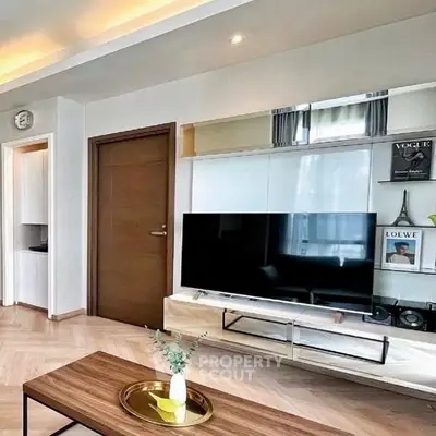 Modern living room with stylish decor and large TV, perfect for relaxation.