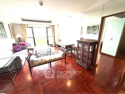 Spacious living room with elegant wooden flooring and stylish furniture, featuring large windows for natural light.