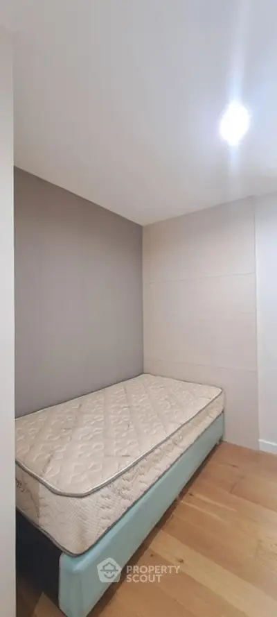 Cozy minimalist bedroom with single bed and wooden flooring