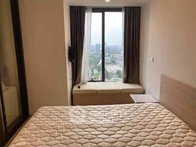 Cozy bedroom with city view, featuring a comfortable bed and large window for natural light.