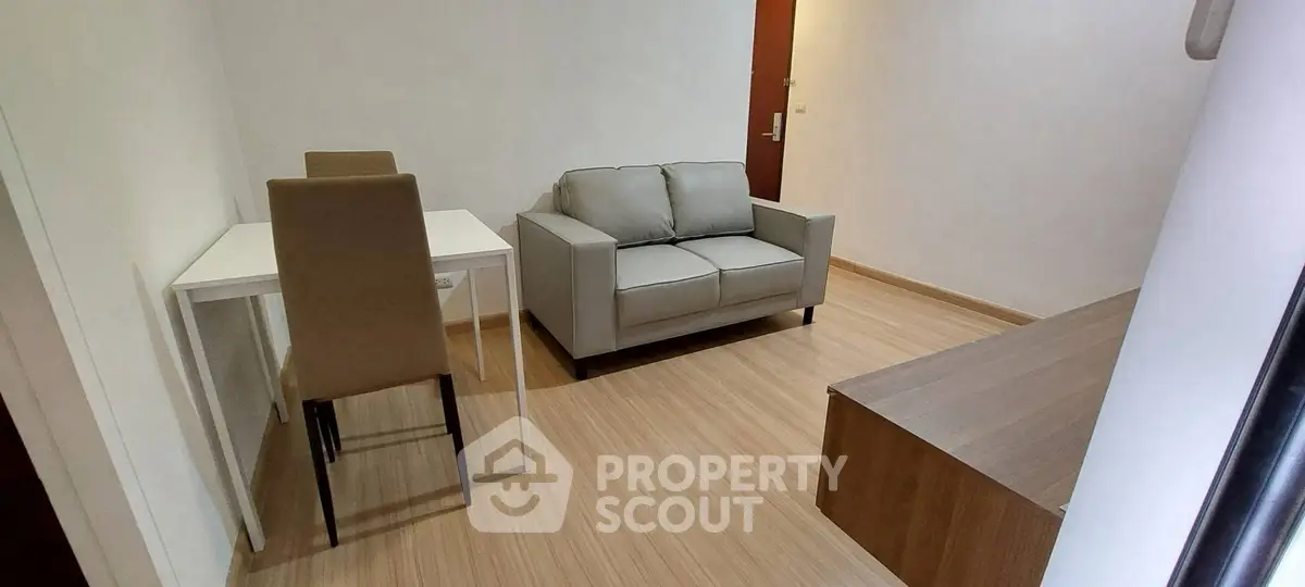 Cozy living room with modern sofa and dining area in a compact apartment.