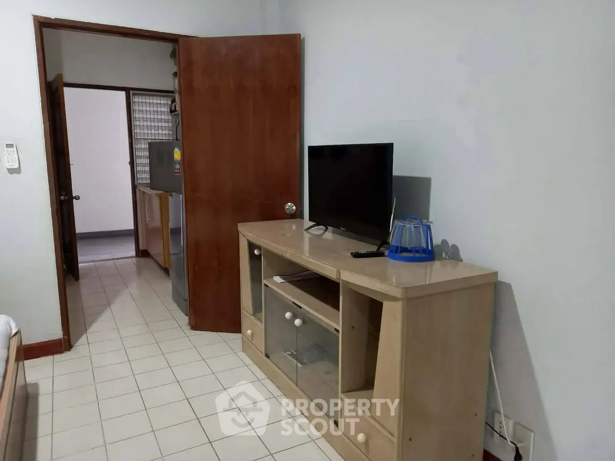 Cozy living room with TV stand and open kitchen view in modern apartment.