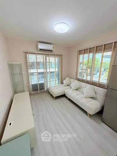 Modern living room with cozy sofa and large windows offering natural light and scenic views.