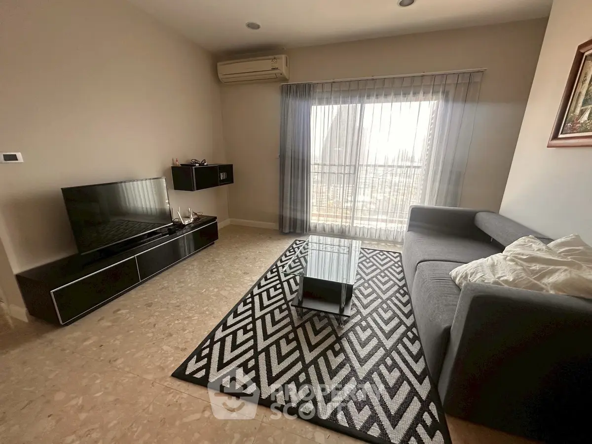 Modern living room with sleek furniture and large window offering natural light.