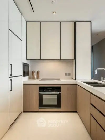 Modern kitchen with sleek cabinetry and built-in oven in luxury apartment.