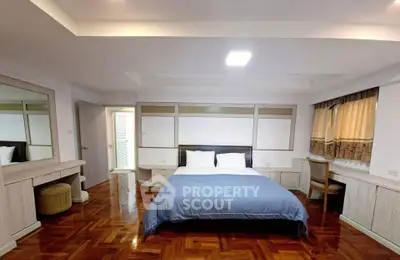 Spacious bedroom with elegant wooden flooring and cozy decor in a modern apartment.