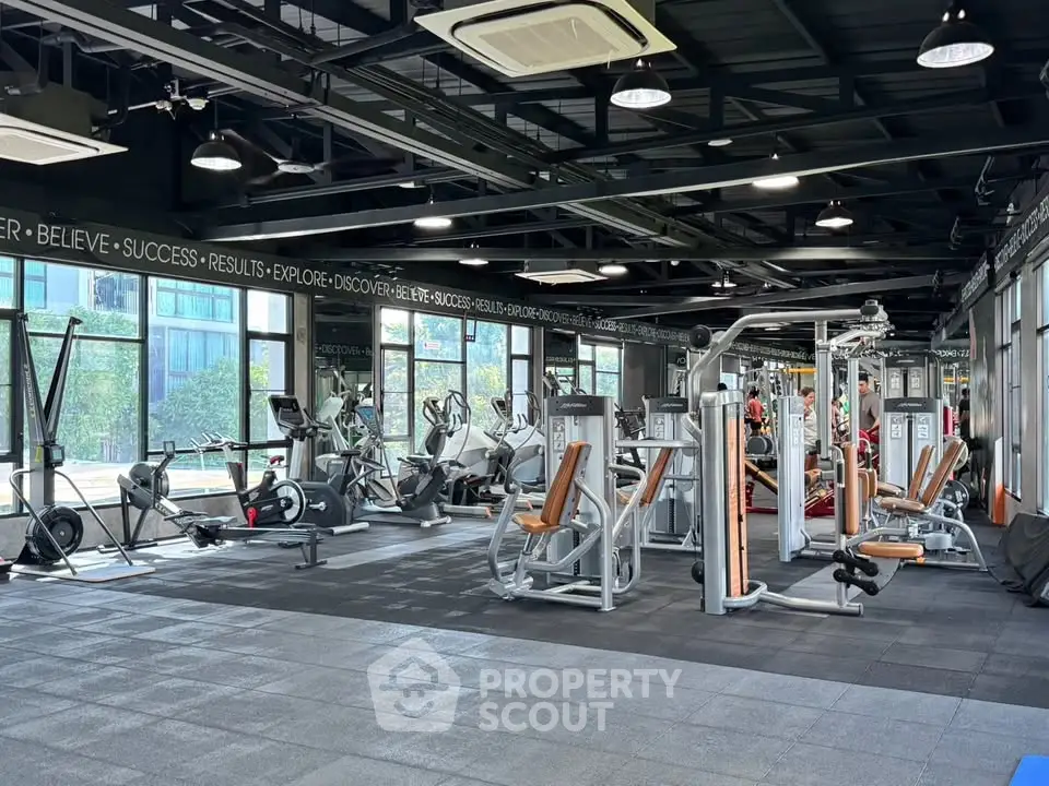 Spacious modern gym with state-of-the-art fitness equipment and large windows for natural light.