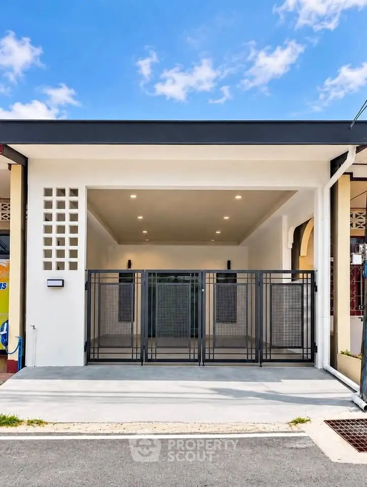 Modern residential building entrance with sleek design and gated parking area.