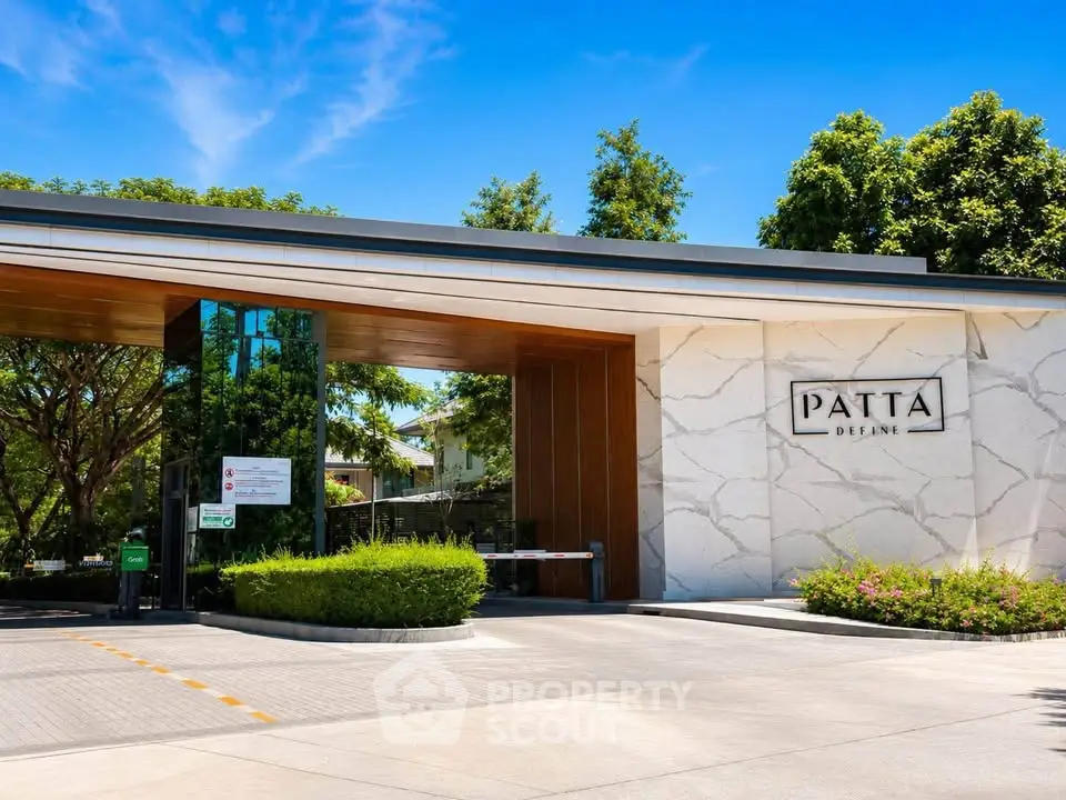 Modern entrance of luxury residential building with sleek design and lush greenery.