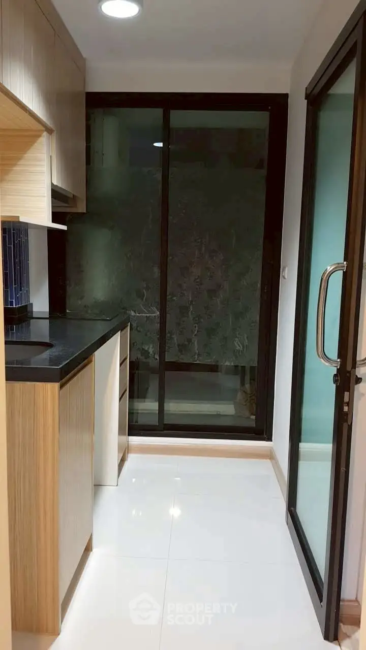 Modern kitchen with sleek cabinetry and large glass sliding door for natural light.